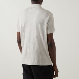 Model wearing Boss Green Label light beige polo shirt, back view, with tonal geometric pattern and short sleeves, styled with black shorts.