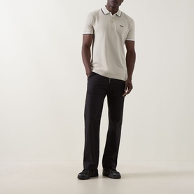 Model wearing Boss Green Label light beige cotton polo with dark tipping detail, styled with black trousers and black shoes.
