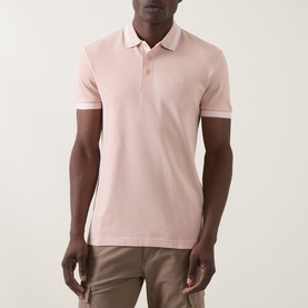 Model wearing Boss Green Label Paddy Logo Tipped Polo Shirt in light pastel orange with tipped collar and short sleeves, styled with beige chinos