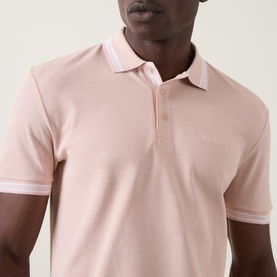 Model wearing Boss Green Label Paddy Logo Tipped Polo Shirt in light pastel orange, with contrast tipped collar and cuffs, logo detail on chest.