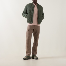 Model wearing Boss Green Label Paddy Logo Tipped Polo Shirt in Light Pastel Orange, styled with green quilted jacket, brown cargo trousers and dark