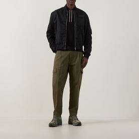 Model wearing Boss Green Label Philix GOC Logo Zip Polo in black, styled with olive cargo trousers and grey chunky trainers.