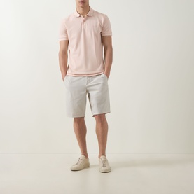 Model wearing Boss Green Label Light Pastel Orange cotton polo shirt, styled with light grey shorts and cream trainers