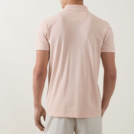 Model wearing Boss Green Label polo in light pastel orange, 100% cotton, rear view, styled with light grey trousers