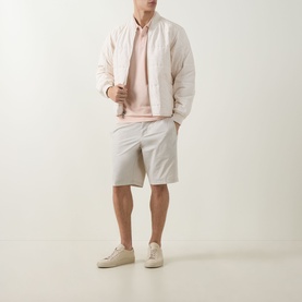 Model wearing Boss Green Label Light/Pastel Orange cotton polo, styled with a pale pink bomber jacket and light grey chino shorts.
