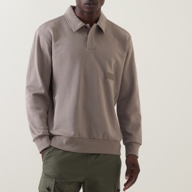 Model wearing Boss Green Label long-sleeve polo sweatshirt in light pastel green, styled with olive cargo trousers
