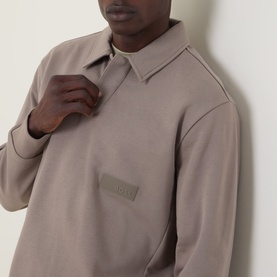 Model wearing Boss Green Label polo in light pastel green, cotton blend with collar and tonal branded chest patch, styled close-up shot