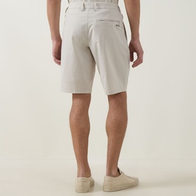 Model wearing Boss Green Label light beige shorts, rear view, styled with cream slip-on shoes. Slim fit with back welt pocket detail.