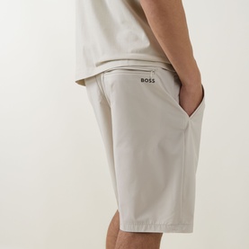Model wearing Boss Green Label light beige shorts, side view showing logo detail and hand in pocket, styled with white tee
