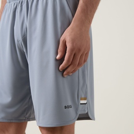 Model wearing Boss Green Label Game Nine Logo Active Shorts in dark grey, with signature-stripe detail and BOSS logo visible at hem.