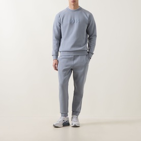 Model wearing Boss Green Label Hadiko Logo Track Pants in dark grey, styled with matching grey sweatshirt and white trainers