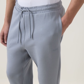 Model wearing Boss Green Label Hadiko Logo Track Pants in dark grey, showing drawstring waist, side pockets and tonal logo detail.