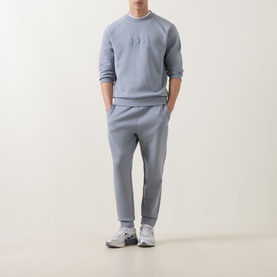 Model wearing Boss Green Label Hadiko Logo Track Pants in dark grey, styled with matching crew neck sweatshirt and white trainers.
