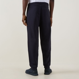 Model wearing Boss Green Label JT Logo Sweatpants in dark blue, slim-leg with cuffed ankles, paired with navy trainers.