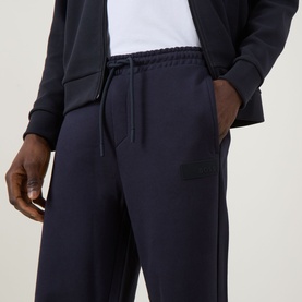 Model wearing Boss Green Label JT Logo Sweatpants in dark blue, slim-leg with drawstring waist, styled with matching zip-through hoodie.