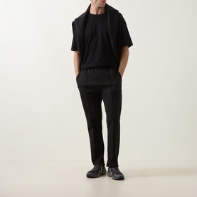 Model wearing Boss Green Label black sweat bottoms with matching black T-shirt and jacket tied over shoulders, styled with dark trainers.