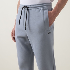 Model wearing Boss Green Label dark grey sweat bottoms with black drawstring waistband, side pockets, and logo detail at thigh.