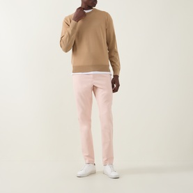 Model wearing Boss Green Label GOC Swing L Trousers in light pastel orange, slim-leg fit, styled with camel crew-neck knit and white trainers