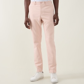 Model wearing Boss Green Label GOC Swing L Water-Repellent Trousers in light pastel orange, slim-leg, styled with white trainers