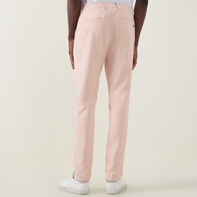 Model wearing Boss Green Label GOC Swing L Water-Repellent Trousers in Light Pastel Orange, slim-leg, rear view, with white trainers