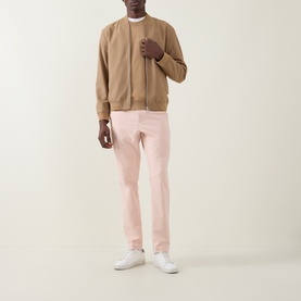 Model wearing Boss Green Label GOC Swing L Trousers in light pastel orange, slim-leg fit, styled with a camel bomber jacket and white trainers