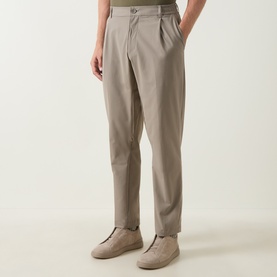 Model wearing Boss Green Label TR Commuter Pleated Trousers in light pastel green, tapered leg with front pleats, styled with beige trainers
