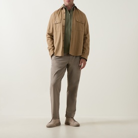 Model wearing Boss Green Label TR Commuter Pleated Trousers in light pastel green, styled with a tan overshirt and olive polo.