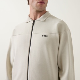 Model wearing Boss Green Label light beige zip-through knit jacket with collar and logo embroidery, close-up detail shot