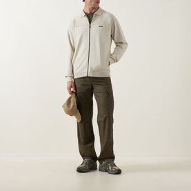 Model wearing Boss Green Label Light Beige zip-through knit jacket, styled with dark olive cargo trousers and grey hiking boots.