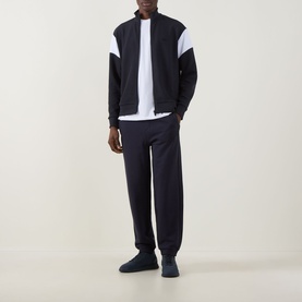 Model wearing Boss Green Label Union Skaz Zip Hoodie in dark blue with white contrast shoulder panels, styled with matching dark blue joggers and