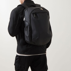 Model carrying Hugo Boss Jace Logo Backpack in black with gunmetal-tone hardware and zipped front pocket, styled with black jacket