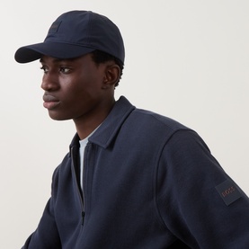 Model with Hugo Boss Derrel-N-TW Baseball Cap in dark blue, six-panel construction with peak visor and logo badge, styled with navy jacket