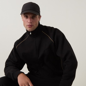 Model with Hugo Boss Pryimus Logo Cap in black, curved peak with contrast grey trim, worn with black zip-neck sweatshirt