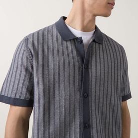 Model wearing Hugo Boss Orange Kodd Stripe Shirt in dark blue, short-sleeve knit with vertical stripes, flat collar and button fastening