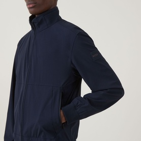 Model wearing Hugo Boss Orange Qlik Logo Windbreaker in dark blue with funnel neck, front zip, and tonal logo badge on sleeve