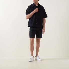 Model wearing Hugo Boss Orange dark blue short-sleeve casual shirt with matching shorts and white trainers.