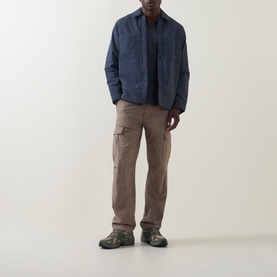 Model wearing Hugo Boss Orange Lody Regular Fit Overshirt in dark blue with chest pockets, styled with taupe cargo trousers and hiking shoes.