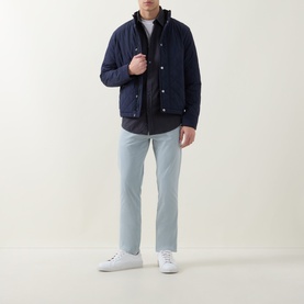 Model wearing Hugo Boss Orange Relegant Dark Blue casual shirt, styled with navy quilted jacket, light blue trousers and white trainers.