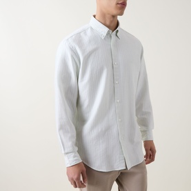 Model wearing Hugo Boss Orange casual shirt in Open Green, long-sleeved cotton blend with button-down collar, styled with beige trousers