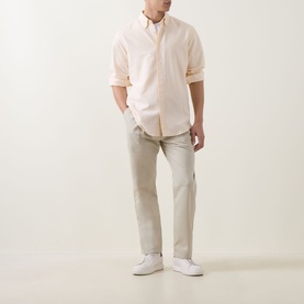 Model wearing Hugo Boss Orange casual shirt in light pastel orange with beige chinos and white trainers.