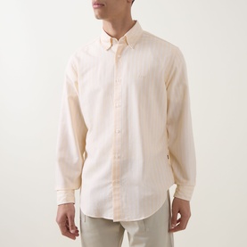Model wearing Hugo Boss Orange casual shirt in light pastel orange, long-sleeved with button-down collar, styled with light beige trousers.