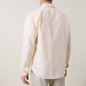Model wearing Hugo Boss Orange casual shirt in light pastel orange, rear view, relaxed fit with subtle texture, styled with grey trousers