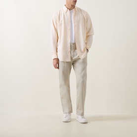 Model wearing Hugo Boss Orange casual shirt in light pastel orange with cream trousers and white trainers