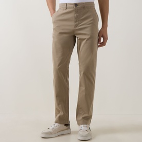 Model wearing Hugo Boss Orange light pastel brown cotton chino trousers with a slim fit, styled with white trainers.
