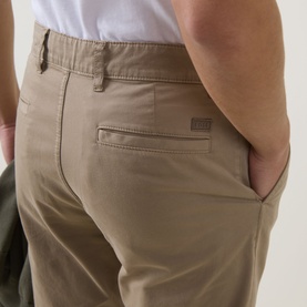 Model wearing Hugo Boss Orange light pastel brown cotton chino trousers, close-up of rear pocket detail with small branded tab