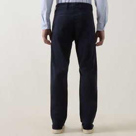 Model wearing Hugo Boss Orange dark blue cotton chino trousers, rear view, styled with a light blue shirt and white trainers.