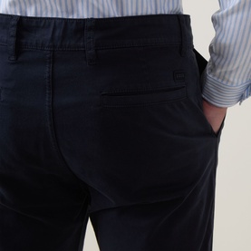 Model wearing Hugo Boss Orange dark blue cotton chino trousers, back view showing rear pocket detail, styled with a striped shirt.
