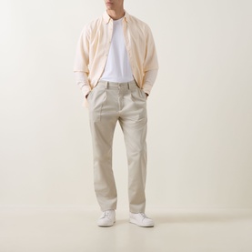 Model wearing Hugo Boss Orange light beige chino trousers with a cream bomber jacket, white tee and white trainers.