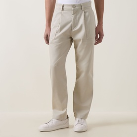 Model wearing Hugo Boss Orange light beige chino trousers with pleat front and straight leg, styled with white trainers.