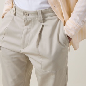 Model wearing Hugo Boss Orange light beige chino trousers with pleat front, button waist, and front pockets, styled with a beige jacket.
